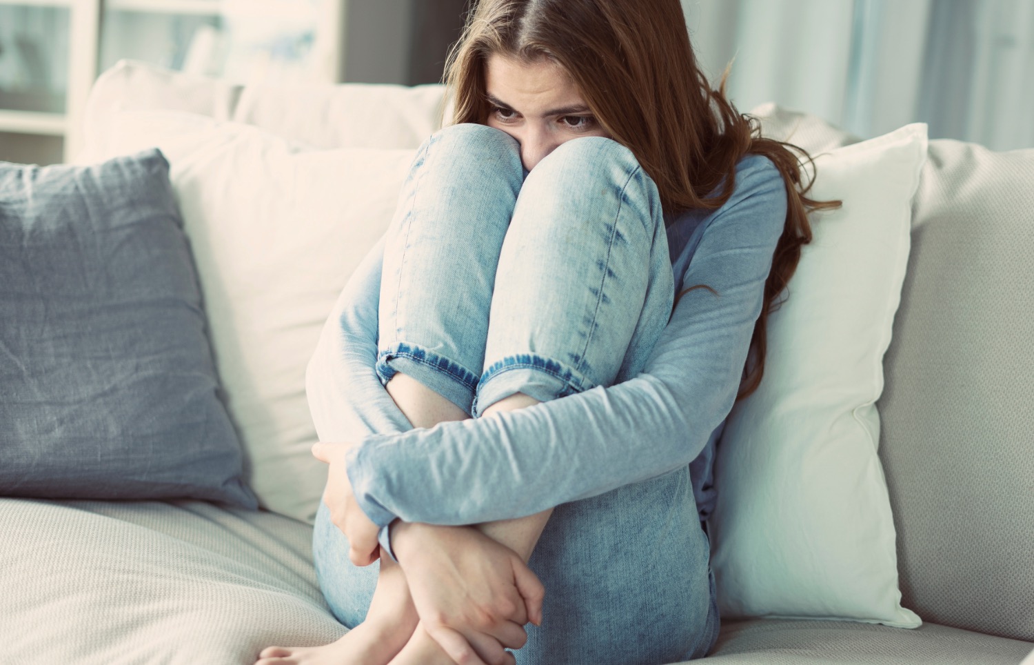 Femme repliée sur un canapé exprimant anxiété et fatigue liées aux troubles vestibulaires