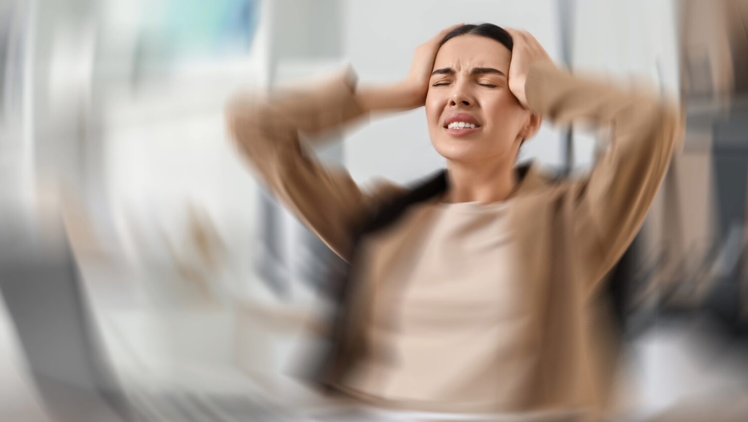 Femme tenant sa tête à deux mains lors d'une crise de vertige — page FAQ sur les troubles vestibulaires