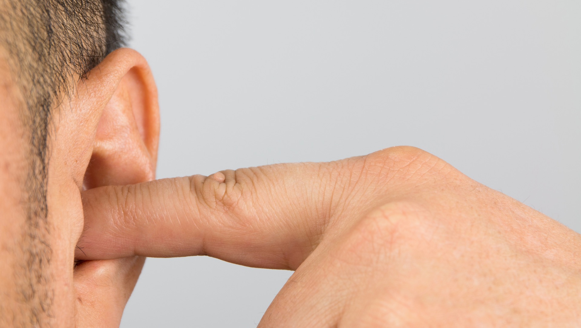 Gros plan d'une oreille avec doigt — hypoacousie et sensation d'oreille bouchée