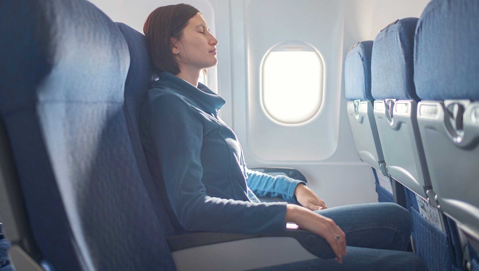 Femme en avion les yeux fermés souffrant du mal des transports — cinétose