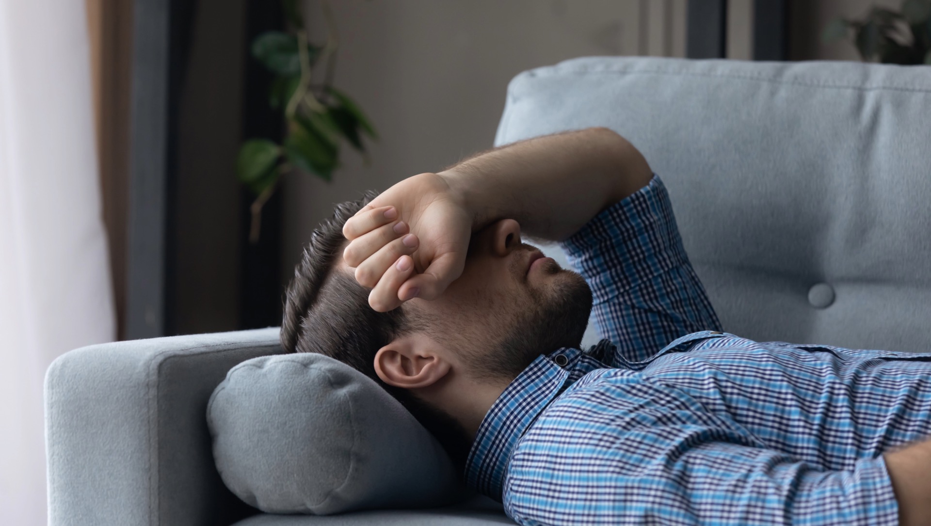 Homme allongé bras sur les yeux souffrant d'une migraine vestibulaire