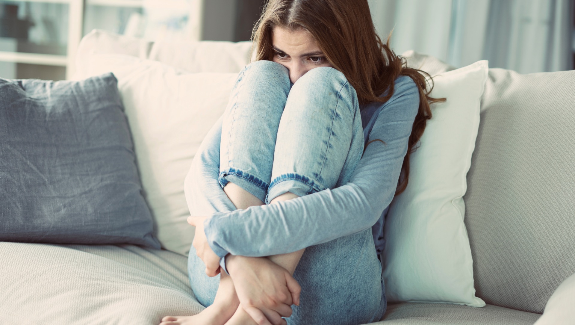 Jeune femme repliée sur un canapé exprimant anxiété et fatigue chroniques
